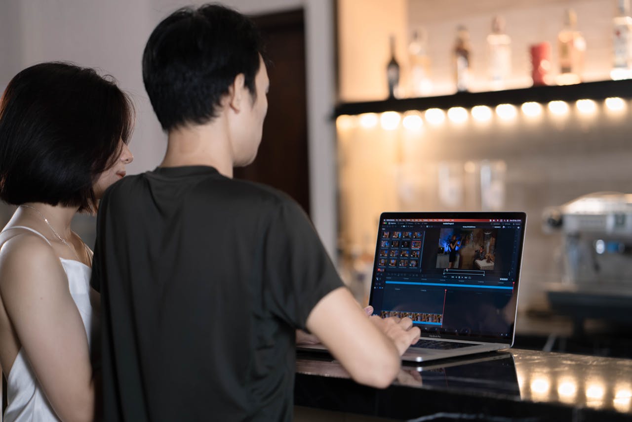 Man and Woman at a Bar Counter Using a Laptop